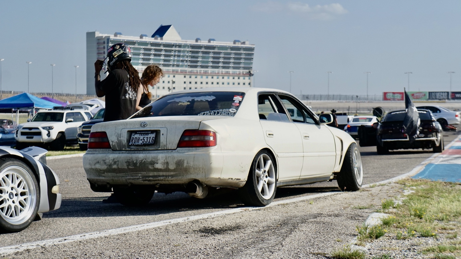 White sedan with track paddock in background