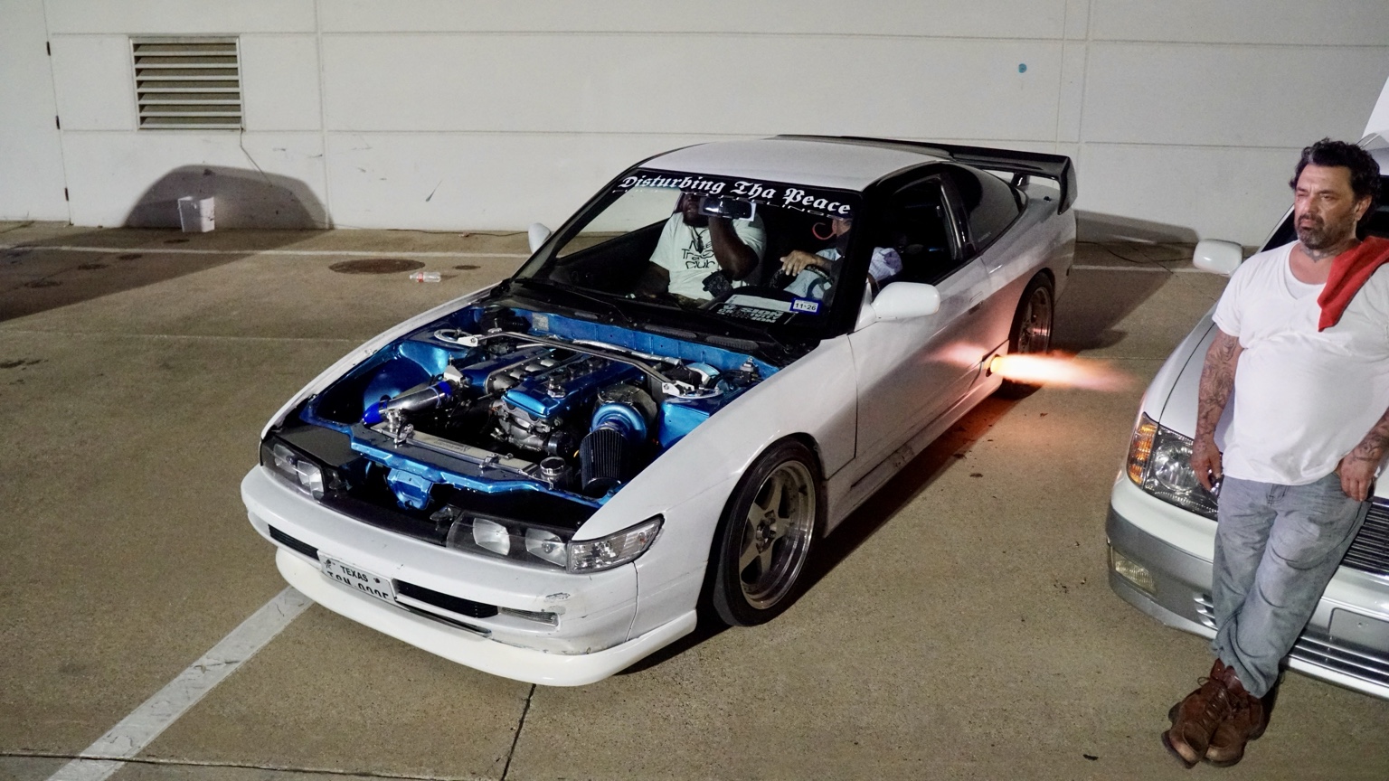 White modified Nissan 240SX with exposed engine and exhaust flame